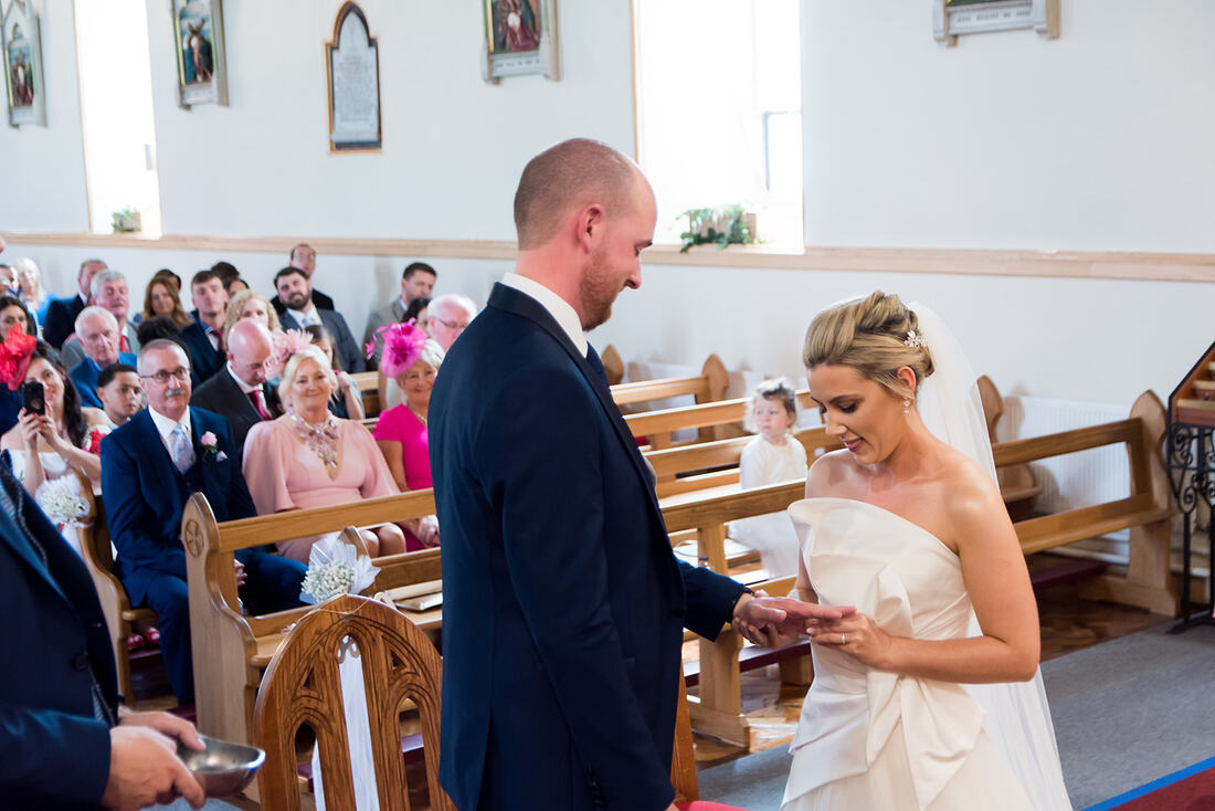 Clare Wedding Photographer | A bride and groom exchange rings at the alter