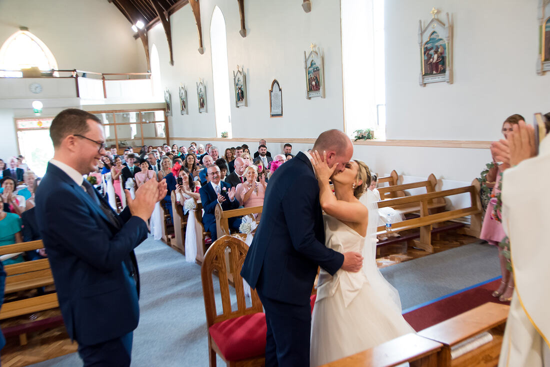 Clare Wedding Photographer | A bride and groom share their first kiss at the alter