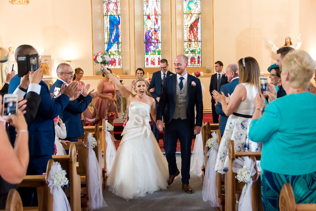 Bride and Groom celebrate getting married by walking down the aisle in a County Clare Wedding
